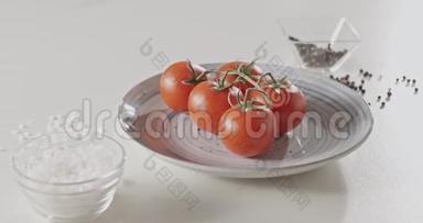 4K全景慢镜头，白色餐桌上蓝色<strong>陶瓷盘</strong>上的樱桃西红柿特写，胡椒